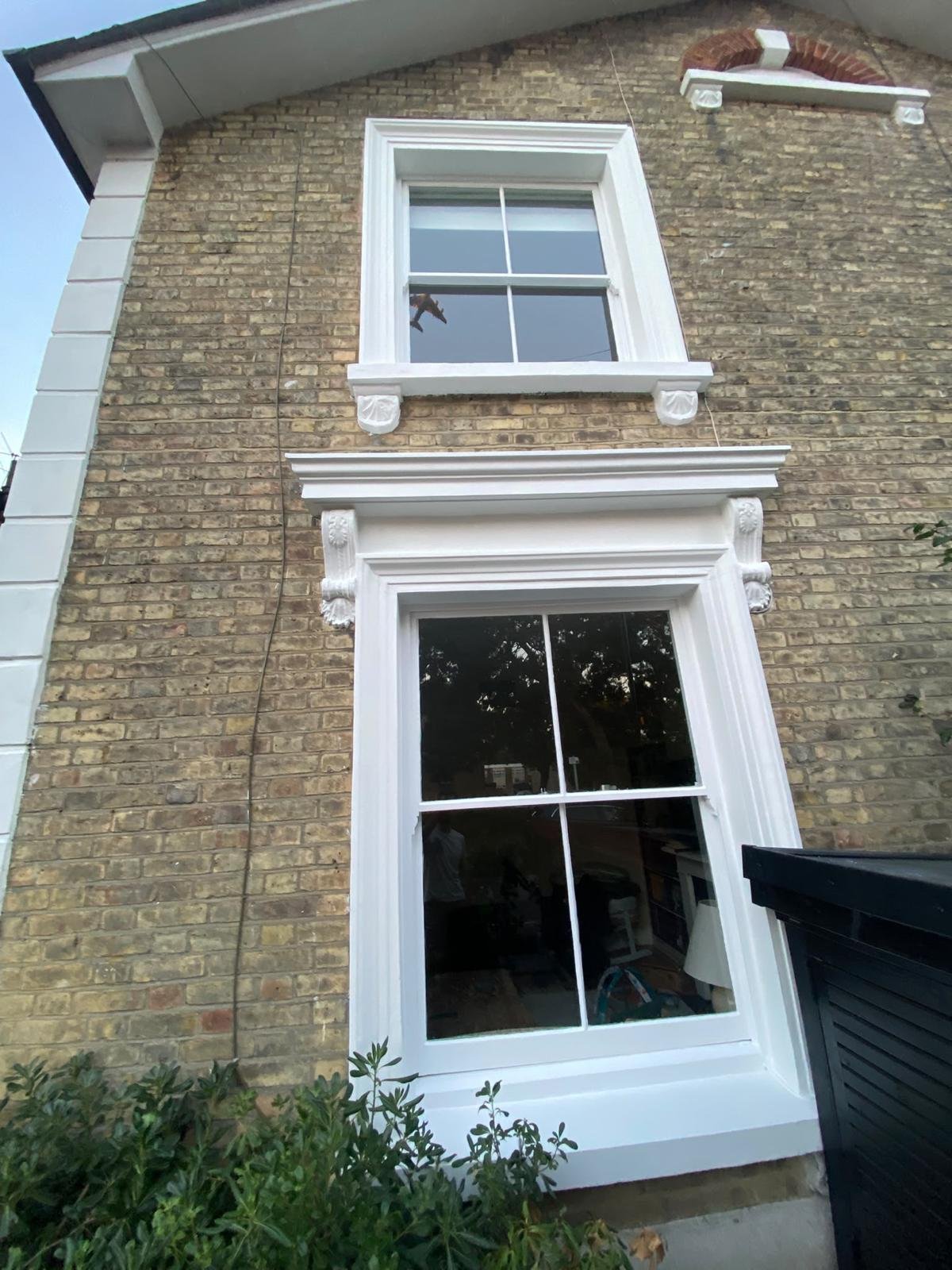 Project 01, after: Brick house exterior with freshly painted white window surrounds and decorative trim