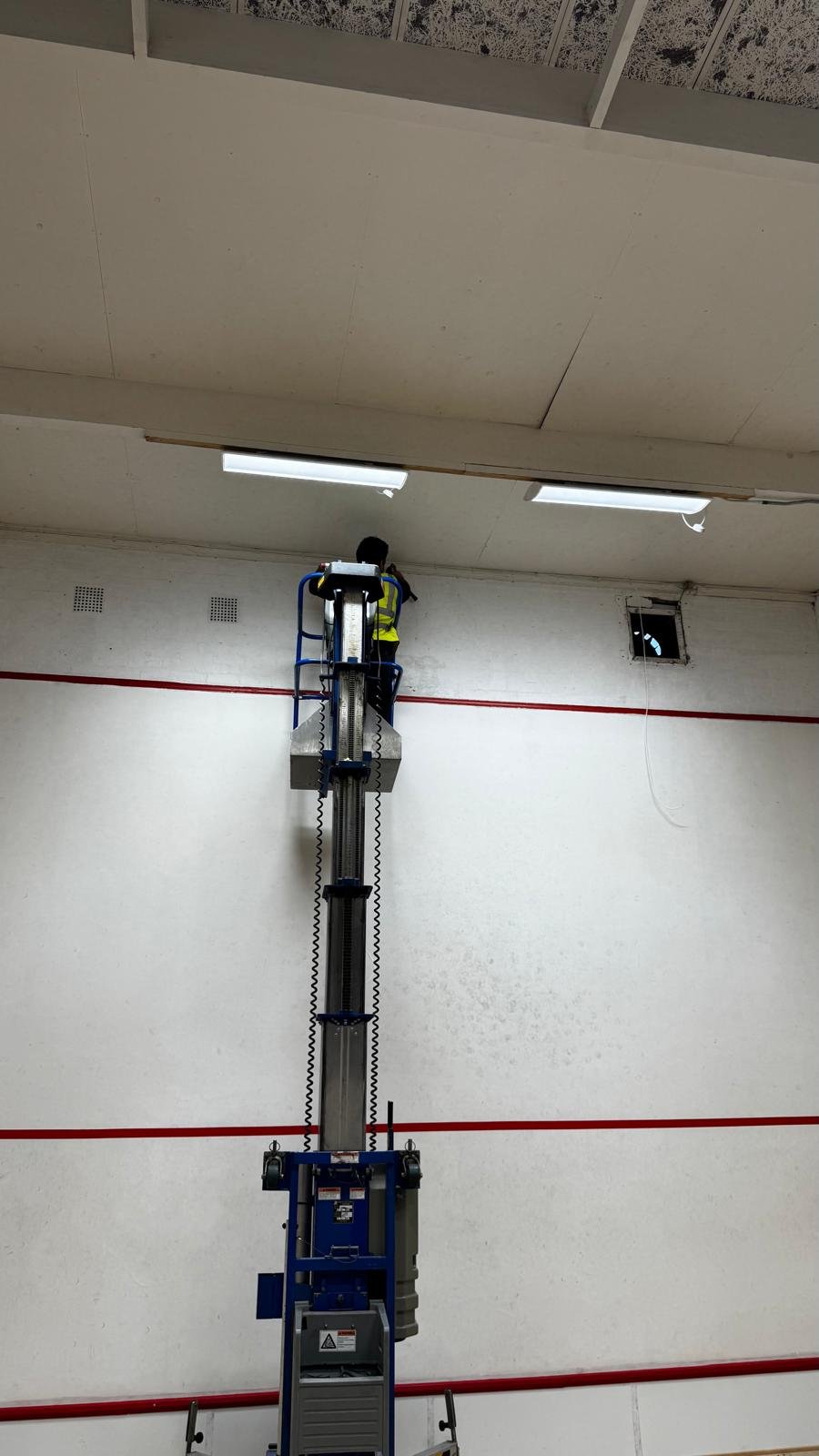 Project 03, after: Painter using a platform lift to work on a high interior wall